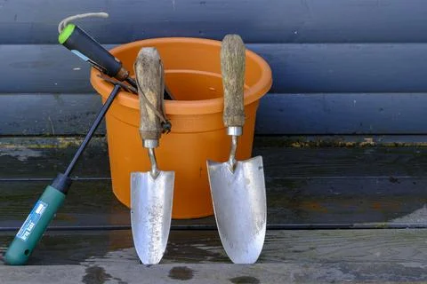 Gardening tools rest beside a bright orange bucket Stock Photos