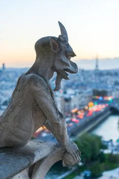 Gargoyle watching Eiffel tower and Paris at dusk Stockfoto's