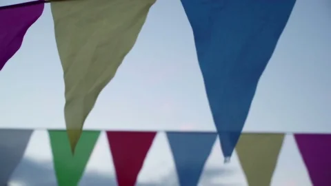Garland of multi colored flags of triangular shape sways in evening sky Stock-Footage 84867185