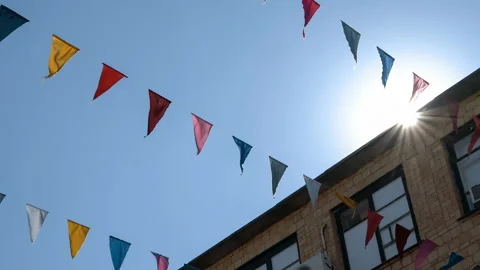 Garland of multi colored flags of triangular shape sways in the blue sky against Stock Footage 87732574