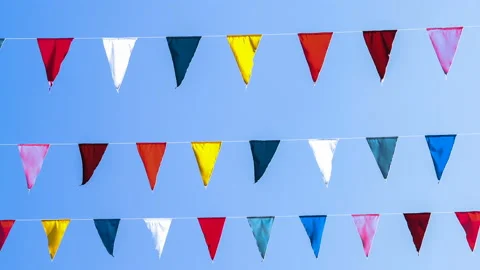 Garland of multi colored flags of triangular shape sways in the blue sky against Stock Footage 87732807
