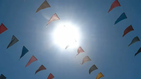 Garland of multi colored flags of triangular shape sways in the blue sky against Stock Footage 87733101