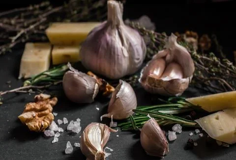 Garlic on a black background. Nuts, cheese, rosemary and thyme. Ingredients f Stock Photos