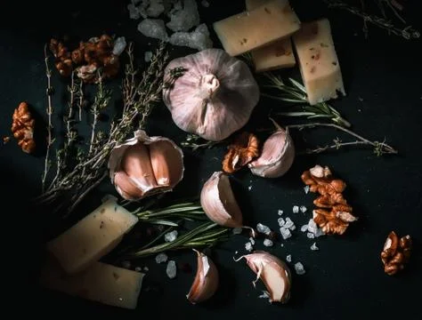 Garlic on a black background. Nuts, cheese, rosemary and thyme. Ingredients f Stock Photos
