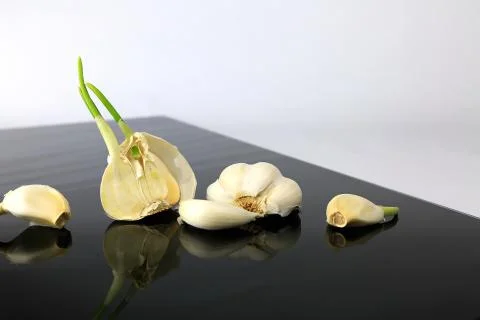 Garlic on a black plate wanders across the picture Stock Photos