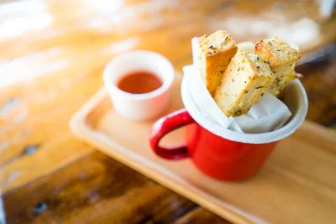 Garlic Bread In a red enamel container, on a Thai wooden table Stock Photos