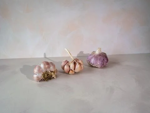 Garlic bulbs with dramatic light and shadow on textured surface Stock Photos