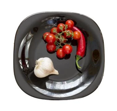 Garlic, chilli, tomato on a plate Stock Photos