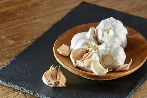 Garlic close up on wooden plate on rustic background, shallow depth of field Stock Photos