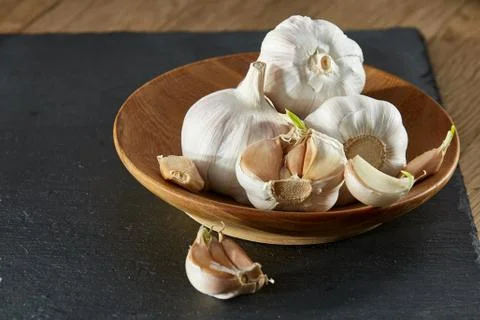 Garlic close up on wooden plate on rustic background, shallow depth of field Stock Photos