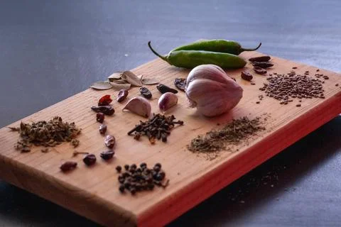 Garlic cloves on rustic table mixed with fresh spices and herbs. Stock Photos