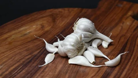 Garlic cloves turning on chopping board Stock Footage