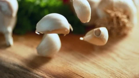 Garlic falling in front of the camera on wooden floor in slow motion Stock Footage 169489446