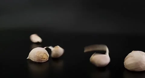 Garlic falls from above on a plane on a black background. Video stock 220105773