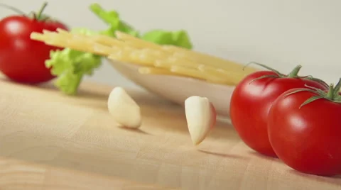 Garlic falls on a table near spaghetti and tomatoes Stock Footage 62681765