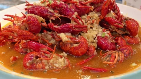 Garlic Glazed Red Crawfish Piled on White Plate with Golden Savory Sauce Stock Footage 339332743
