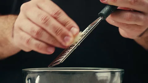 Garlic with grater, Close up of hand grating garlic with a small metal grater Stock Footage 309637580