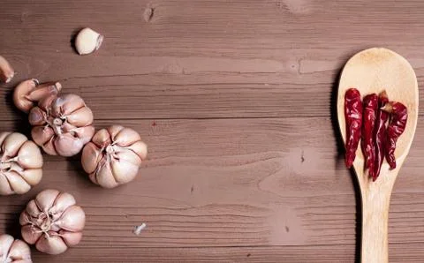 The garlic head put at the left side and wooden spoon with dried pepper put a Stock Photos