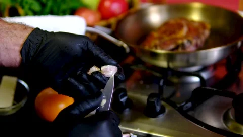 Garlic peeled with kitchen knife by chef wearing black gloves beside hot stove Video stock 346183549