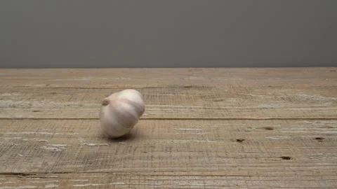 Garlic rolling on a wooden surface on a gray background. Видео 266495229