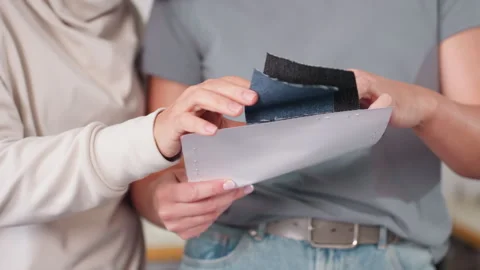 Garment makers checking material types together during design selection process Stock Footage 307135784