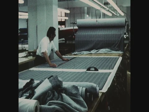 Garment worker pulling rolls of cloth onto table for cutting, Abe Schrader, Video stock 82520433