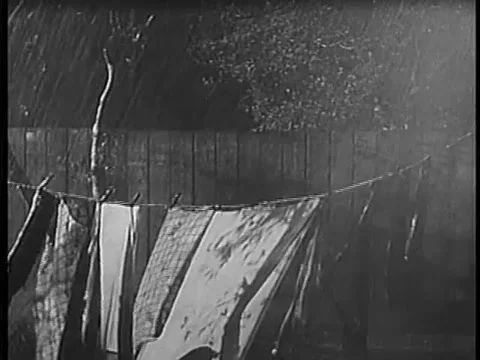 Garments on clothesline getting soaked during rainstorm, 1940s Video stock 64630075