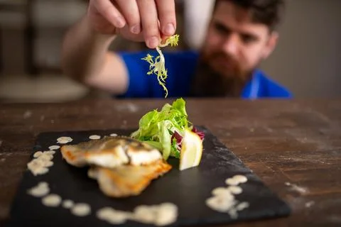 Garnish being added to a plated fish dish by a chef Stock Photos