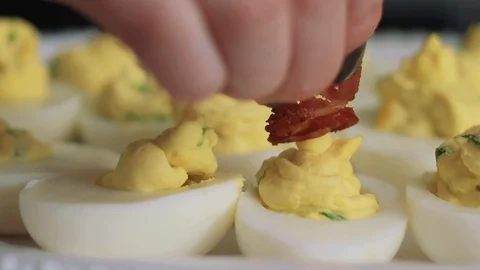 Garnishing deviled eggs with bacon Stock Footage 85476202