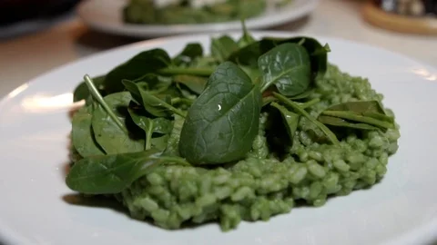 Garnishing green spinach risotto with dried pumpkin seeds, SLOW MOTION Stockbeeldmateriaal 123290006
