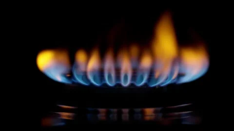 Gas burner lights up on black background. Slow motion UHD shot of gas stove Video stock 257566015