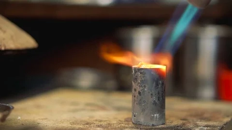 Gas flame flow softens the metal on a wooden table close up Video stock 72964987