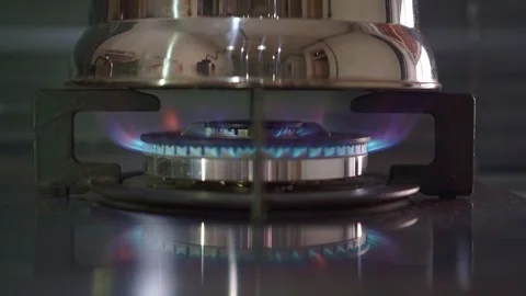 Gas flame ring igniting under metal kettle, blue fire burning, home kitchen Stock Footage 343424246