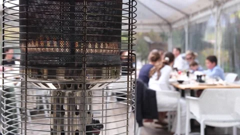 A gas heater with blurry view of groups of people eating at the background Stock Footage 273566847