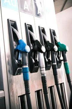 Gas pumps of different colors hooked into place. Stock Photos