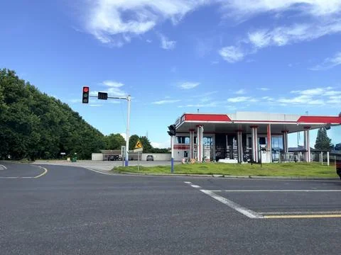 Gas Station at Empty Intersection with Red Traffic Light and Blue Sky 스톡 사진