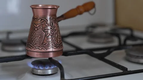 Gas stove burner igniting under copper cezve with turkish coffee Vídeos de archivo 335076844