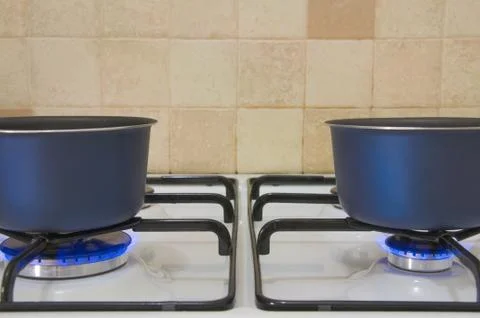 Gas stove with two burning burners, which are heated pots. Stock Photos