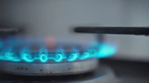 A gas stoves burner ignites producing a blue flame as it burns gas for cooki Stock Footage 331313249
