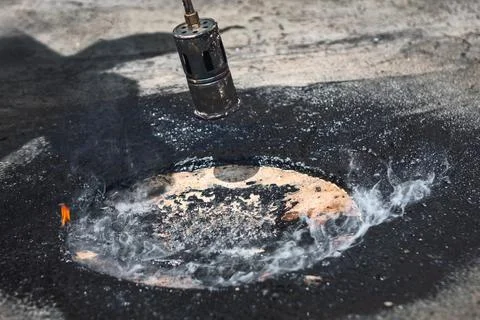 Gas torch burns through a flat roofing surface Stock Photos