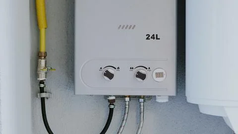 Gas water heater with control knobs and pipes mounted on a wall Stockfoto's