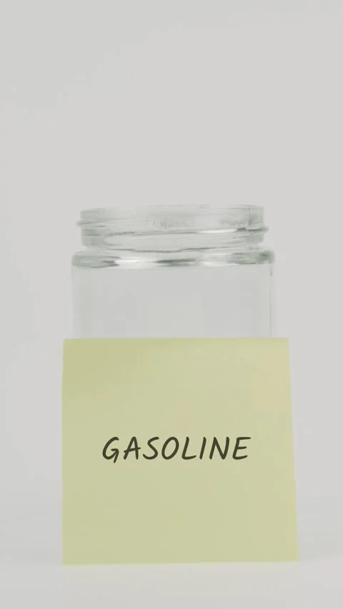 Gasoline text or word on yellow sticky note attached to glass jar with hand Stock Footage 311738077