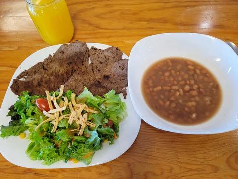Gastronomic Harmony: Steak, Salad, and Frijol Soup on Wooden Surface Stock Photos