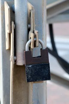 The gate is closed with a rusty padlock. Object security. Stock Photos
