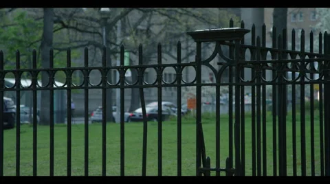 Gate in focus, blocking out-of-focus building with grass and traffic behind Stock Footage 56951380