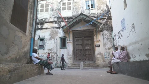 Gate of an old building and locals sitting in the alley Stock Footage 85778846