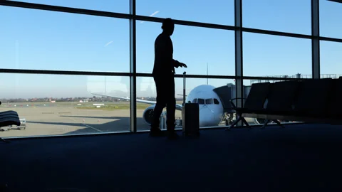 Gate open, man take suitcase and walk to board the plane, silhouetted shot Stock Footage 320118011