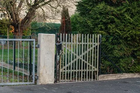 Gate opens to a garden with trees and green grass in daylight Stock Photos