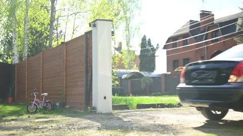 Gate of a private property opens, a black sedan drives in and out of the house Stock Footage 275221964