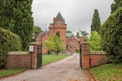 The gate to a romantick red castle inside a park on a green lawn Stock Photos